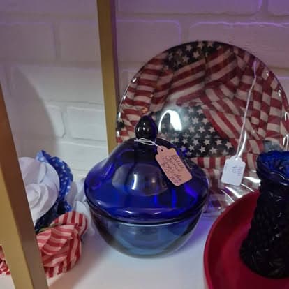 A blue glass bowl sitting on a shelf next to a red plate.