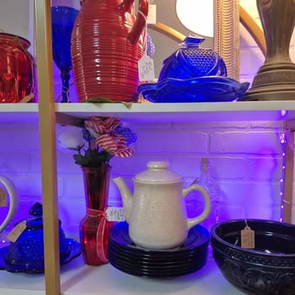 Many different colored vases and bowls on a shelf.