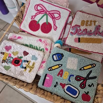 Four purses with different designs on them sitting on a wicker basket.